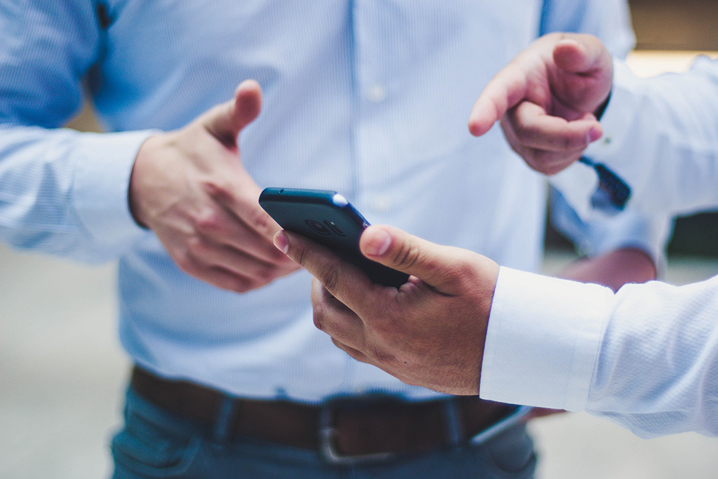 A pair of hands holding a phone and gesturing at the screen