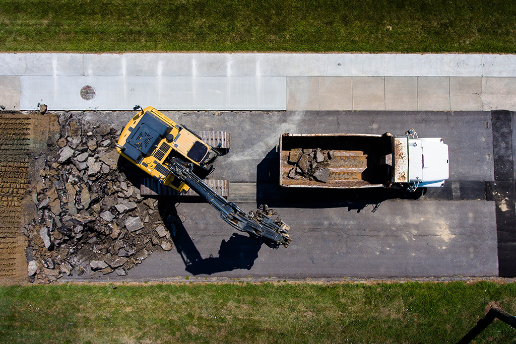 Excavator and dump truck removing old track asphalt